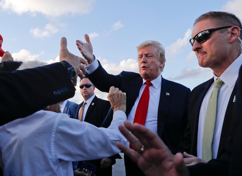 Donald Trump reaches out to greet supporters on the tarmac upon his arrival at Palm Beach International Airport, Thursday, April 18, 2019. AP Photo