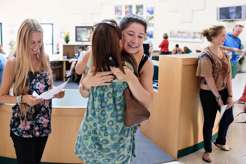 Dubai, August 15, 2013 -  (L to R) Emma Langley checks her year 13 A level results as her mother, Nicky Langley, embraces her classmate, Alice Taylor at Jumeirah College in Dubai, August 15, 2013. (Photo by: Sarah Dea/The National, Story by: Caline Malek) *** Local Caption ***  SDEA150813-A-Levels_Dubai03.JPG