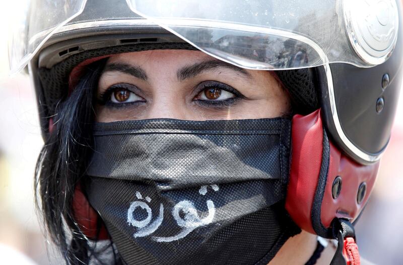 FILE PHOTO: A demonstrator, wearing a mask as a preventive measure against the spread of coronavirus disease (COVID-19), attends a protest against the growing economic hardship and to mark Labour Day in Beirut, Lebanon May 1, 2020. The word "Revolution" reads on the mask. REUTERS/Mohamed Azakir/File Photo