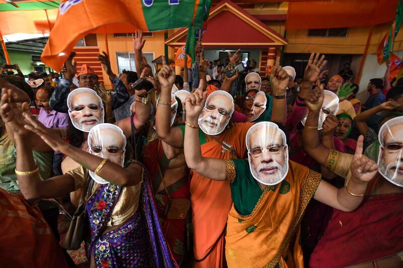 TOPSHOT - Indian Bharatiya Janata Party (BJP) supporters wearing masks of Indian Prime Minister Narendra Modi dance as they celebrate on the vote results day for India's general election at BJP office in Guwahati on May 23, 2019.  Indian Prime Minister Narendra Modi looked on course on May 23 for a major victory in the world's biggest election, with early trends suggesting his Hindu nationalist party will win a bigger majority even than 2014. / AFP / Biju BORO
