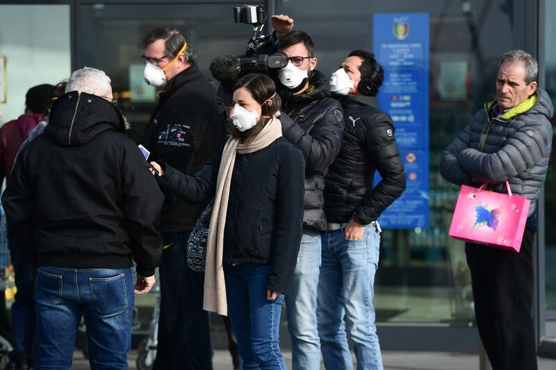 Reporters wearing resppiratory mask interview a resident (L) on February 23, 2020 in the small Italian town of Casalpusterlengo under the shadow of a new coronavirus outbreak, as Italy took drastic containment steps as worldwide fears over the epidemic spiralled.   / AFP / Miguel MEDINA
