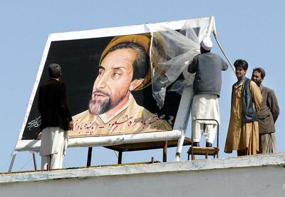 Workers put up a poster of former anti-Taliban commander Ahmad Shah Masood on the building of Kabul International Airport, 03 April 2002.  In homes, in the streets, on car windscreens and even woven into traditional carpets, Masood's chiselled and bearded features keep a watchful eye.     AFP PHOTO/Rosland RAHMAN (Photo by ROSLAN RAHMAN / AFP)