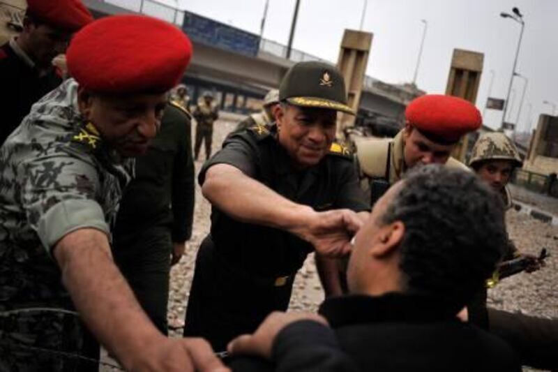 epa02565391 An Egyptian army officer (C) dries the tears of an anti-Mubarak protester while another one (L) pads his shoulders as they negotiate across razor wire on the fringes of Tahrir Square in Cairo, Egypt, on 05 February 2011. Soldiers came into the square, maneuvered three tanks close to the barricades as well and tried to get the activists to tear down their barricades so that the area could be cleaned up and kept open. The activists believe the pro-Mubarak supporters would then be able to invade the square they hold.  EPA/ANDRE LIOHN *** Local Caption ***  02565391.jpg