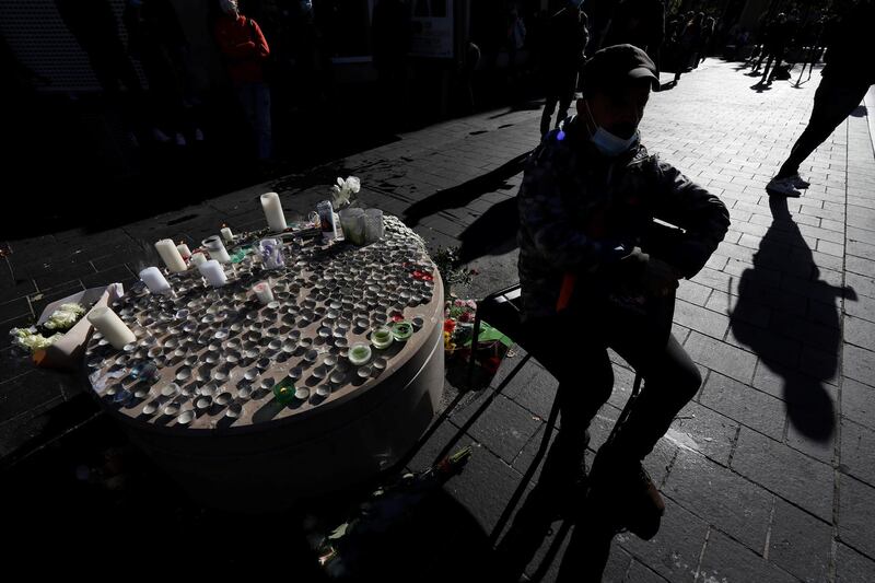 A man sits near candles and flowers placed in tribute to the victims. Reuters