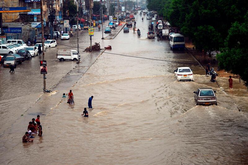 Commuters wade through a flooded street after heavy monsoon rains in Pakistan's port city of Karachi.   AFP