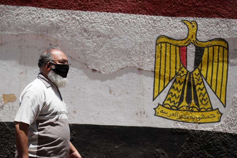A man wearing a protective face mask to prevent the spread of the coronavirus walks next to a wall painted with the colorus of Egypt's flag, after the government made wearing masks mandatory in public places and public transport, in Cairo. Reuters