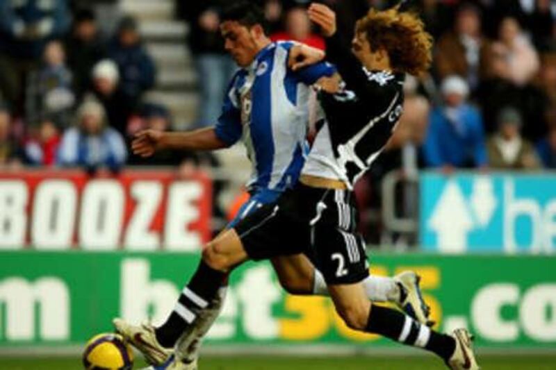 Amr Zaki of Wigan, left, tussles with the Newcastle defender Fabricio Coloccini.