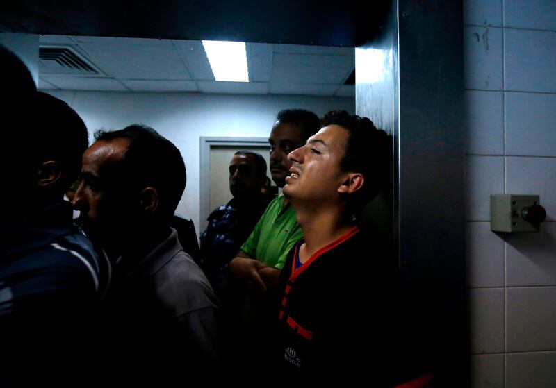 Relatives mourn over the body of Abdel Karim Radwan, who was killed in an Israeli air strike earlier today, at a hospital in Khan Yunis in the southern Gaza Strip on July 19, 2018. A Palestinian was killed in an Israeli strike in the Gaza Strip on Thursday, the enclave's health ministry said, after Israel said one of its aircraft targeted a group launching balloons carrying firebombs. / AFP / SAID KHATIB
