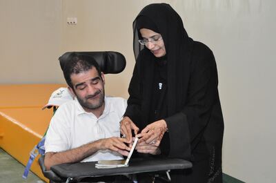 Naema Al Mansouri assists a man with a Braille book during the launch of a reading competition for the blind in Abu Dhabi in 2018. Courtesy Naema Al Mansouri