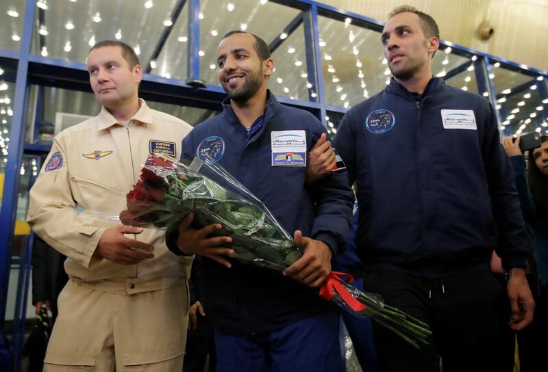 Hazza Al Mansouri with a bouquet of flowers is flanked by Russian space officials.