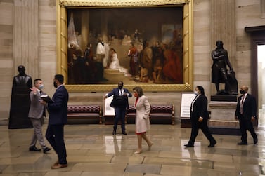 WASHINGTON, DC - DECEMBER 14: Speaker of the House Nancy Pelosi (D-CA) (C) walks past the painting depicting the baptism of Pocahontas before joining fellow members of the House and Senate in the U. S.  Capitol Rotunda for a vigil on December 14, 2021 in Washington, DC.  The senators and representatives observed a moment of silence for the 800,000 Americans who have died of the coronavirus.    Chip Somodevilla / Getty Images / AFP

