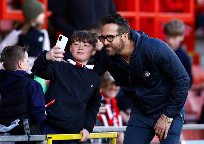 A fan takes a photo with Wrexham co-owner Ryan Reynolds before the match. Reuters