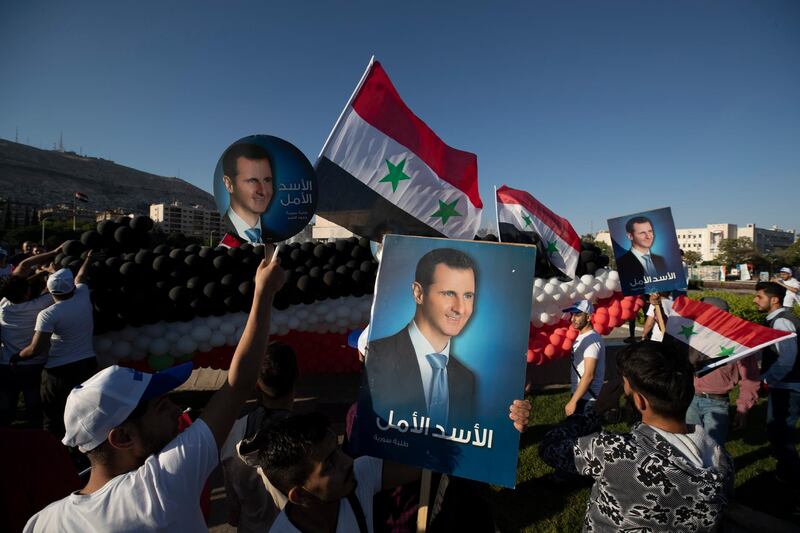 Supporters of Bashar Al Assad hold up images of the president and wave Syrian flags at Umayyad Square. More than 388,000 people have been killed in the civil war, and half the population displaced.