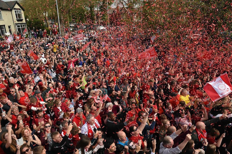 Football fans line the streets waiting to see the Liverpool football team take part in an open-top bus parade. AFP