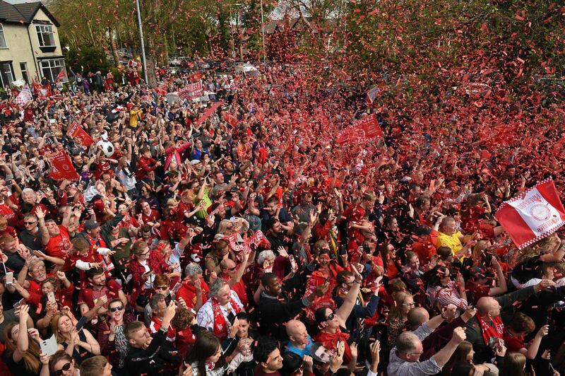 Football fans line the streets waiting to see the Liverpool football team take part in an open-top bus parade. AFP