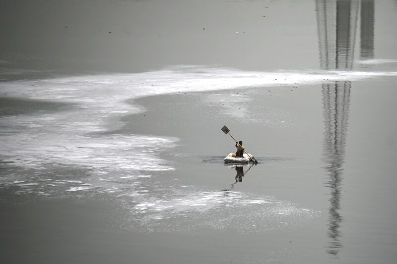 A boy rows a boat across the polluted waters of Yamuna River, laden with foam, on a hot summer day in New Delhi. AFP