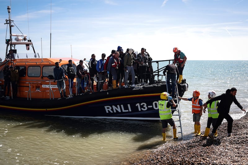 A lifeboat crew helps migrants on to shore at Dungeness on Wednesday, after they were picked up at sea while crossing the English Channel. AFP