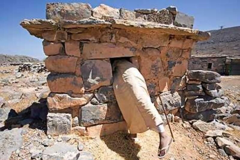Wheat grown in the village is stored in a stone structure, while a Pakistani labourer, below, helps maintain the village's houses.