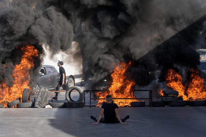 In the West Bank city of Ramallah, tyres burn in the Jalazone refugee camp where two Palestinians were shot dead by Israeli soldiers. The military claims the two tried to ram their car into soldiers during an arrest operation. AP