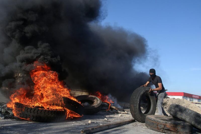 A Lebanese protester takes part in blocking a bridge with flaming tyres on the Sidon-Ghazieh highway amid demonstrations which erupted after the sharp drop of the Lebanese pound on the black market, in Ghazieh. AFP