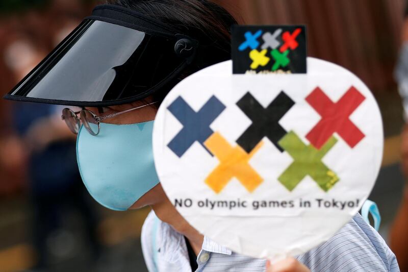 A demonstrator wearing a face mask holds a sign to protest against the Tokyo 2020 Olympic Games a year before the start of the summer games that have been postponed to 2021 due to the coronavirus  outbreak.  Reuters