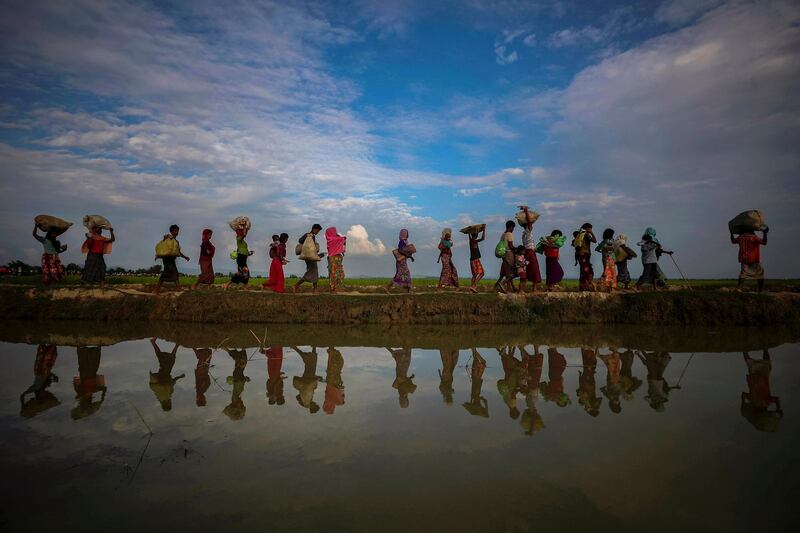 FILE PHOTO: Rohingya refugees are reflected in rain water along an embankment next to paddy fields after fleeing from Myanmar into Palang Khali, near Cox's Bazar, Bangladesh November 2, 2017. REUTERS/Hannah McKay/File Photo