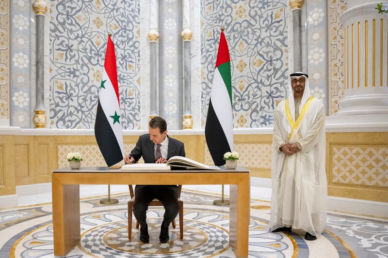 Sheikh Mohamed stands as Mr Al Assad signs a guest book. Presidential Court