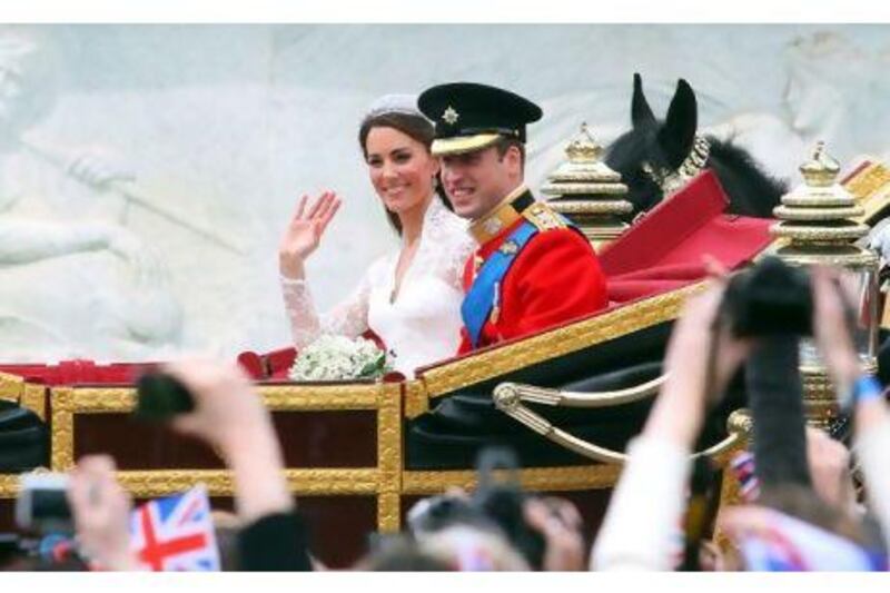 Britain's Prince William and his wife Kate, Duchess of Cambridge, wave as they travel in the 1902 State Landau carriage along the Processional Route to Buckingham Palace.