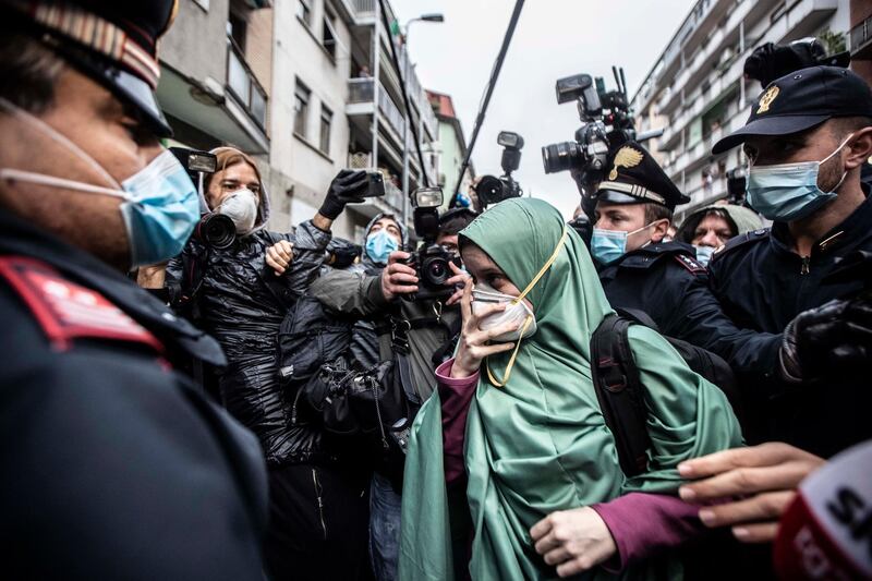 FILE -  In this Monday, May 11, 2020 file photo, Silvia Romano, escorted by Carabinieri officers, arrives at her home wearing the green hijab typical of Somali Muslim women and a surgical mask to guard against COVID-19, in Milan, Italy, Monday, May 11, 2020. A right-wing lawmaker was reprimanded Wednesday for having called a young Italian woman held hostage in Somalia by Muslim extremists a â€œneo-terroristâ€ after she returned home having apparently converted to Islam. Silvia Romano, 24, stepped off an Italian government jet on Sunday wearing the green hijab typical of Somali Muslim women. (AP Photo/Luca Bruno, File )