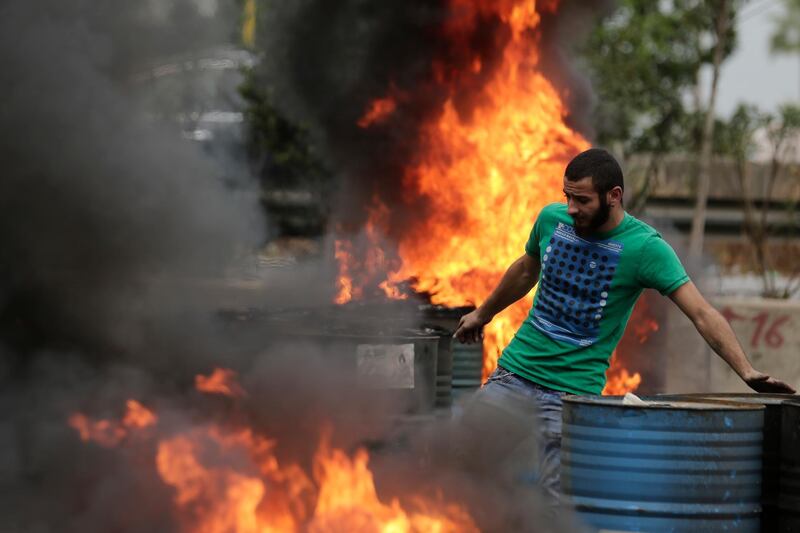 An anti-government protester sets fire to tires to block a highway that links the capital Beirut to northern Lebanon during a protest against the Lebanese government in Zouk Mosbeh, north of Beirut, Lebanon. AP Photo
