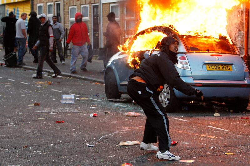 A man throws a rock at riot police in Clarence Road, Hackney, in August 2011. This year marks 10 years since the four days of unrest in London.