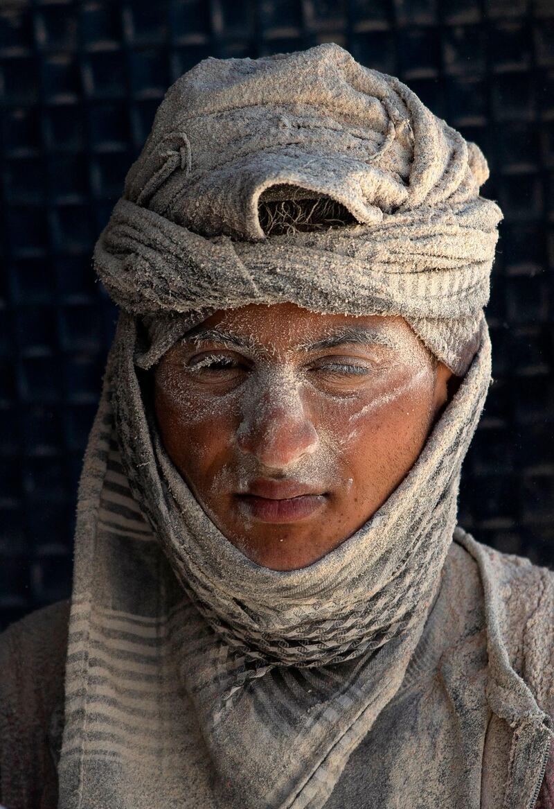 A worker's face is covered in dust as he unloads imported corn at the southern Iraqi port of Umm Qasr near Basra. AFP