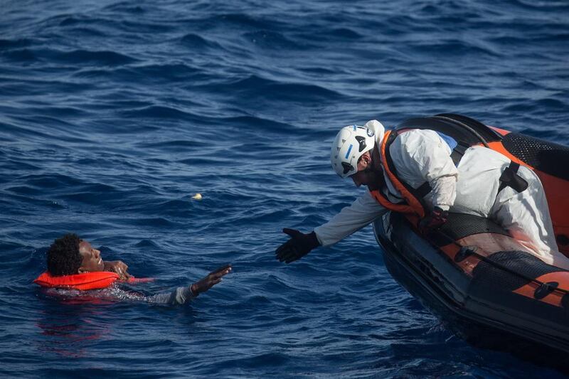 A rescuer from the Migrant Offshore Aid Station ‘Phoenix’ vessel reaches to pull a man out of the Mediterranean Sea off Lampedusa, Italy.  Chris McGrath / Getty Images