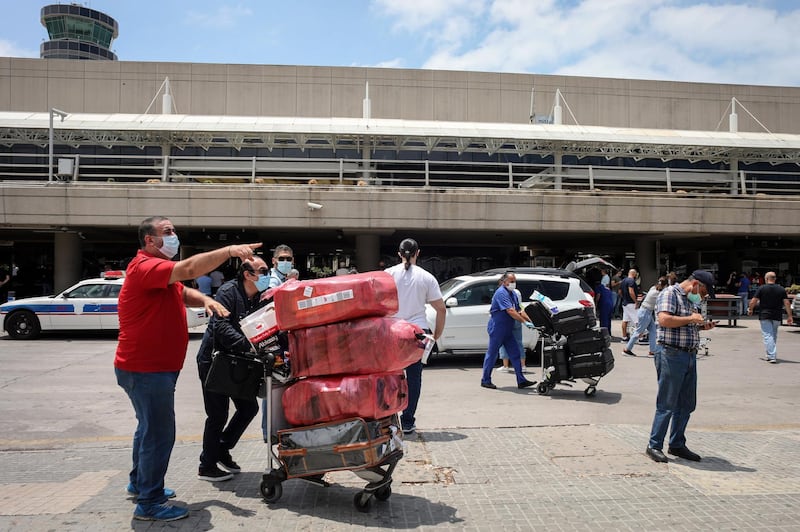 Passengers wearing protective face masks push luggage carts outside the terminal at Rafik Hariri International Airport in Beirut. Bloomberg