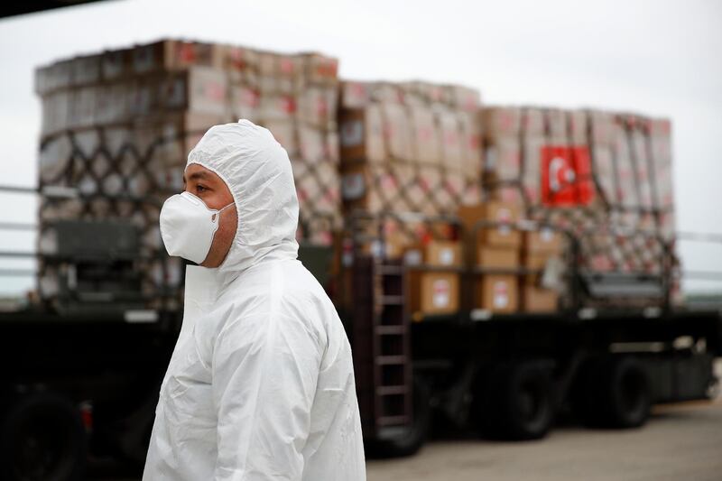 A flight crew member stands in front of a donation of medical supplies from Turkey on April 28, 2020, at Andrews Air Force Base, Maryland. The donation to help fight the new coronavirus in the United States included surgical masks, sanitisers and protective suits. AP Photo