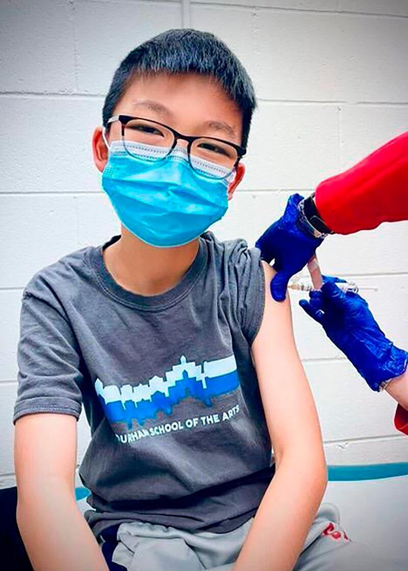 In this Dec. 22, 2020, photo, provided by Richard Chung, his son Caleb Chung receives the first dose of Pfizer coronavirus vaccine or placebo as a trial participant for kids ages 12-15, at Duke University Health System in Durham, N.C.  Pfizer says its COVID-19 vaccine is safe and strongly protective in kids as young as 12. The announcement Wednesday, March 31, 2021 marks a step toward possibly beginning shots in this age group before the next school year. (Richard Chung via AP)