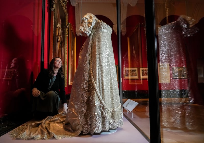 Exhibition curator Anna Reynolds adjusts the earliest surviving British royal wedding dress, worn by Princess Charlotte, at Buckingham Palace. PA