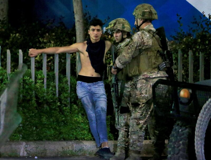 A detained demonstrator stands near Lebanese army soldiers during a protest against growing economic hardship in Sidon, Lebanon. Reuters