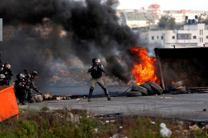 Israeli security forces take aim during clashes with Palestinian demonstrators following a demonstration in the West Bank city of Ramallah on March 16, 2018, as protests continue in the region amid anger over US President Donald Trump's recognition of Jerusalem as its capital.  / AFP PHOTO / ABBAS MOMANI