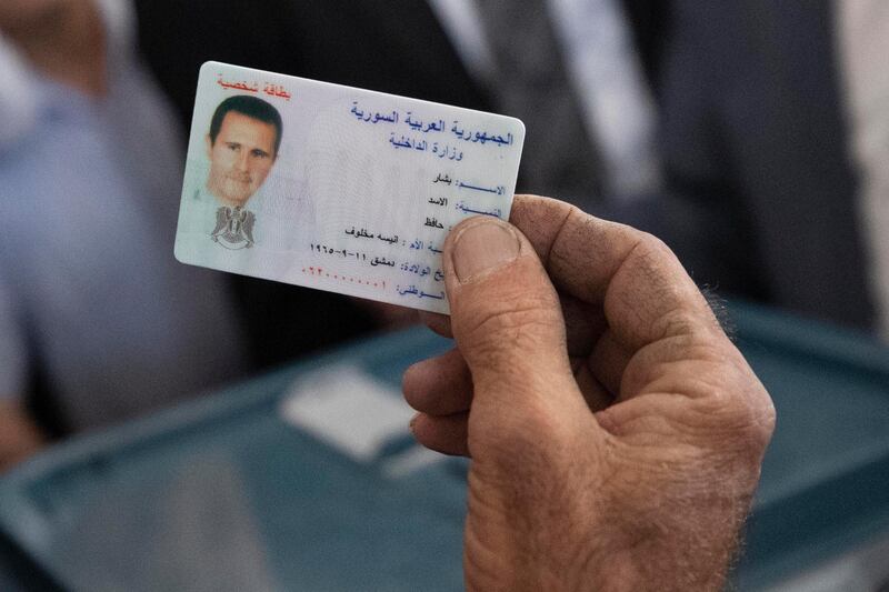 An election official checks President Al Assad's ID, at the polling station where the Syrian leader had gone to vote. AP