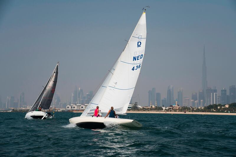 Sailboats taking part in a race catch the wind with the Burj Khalifa, the world's tallest building, seen in the distance in Dubai, United Arab Emirates, Friday, June 19, 2020. Dubai has begun allowing organized sports competitions to take place after locking down over the coronavirus pandemic and the COVID-19 illness it causes. Competitions held Friday at the Dubai Offshore Sailing Club were among the first events to be held. (AP Photo/Jon Gambrell)