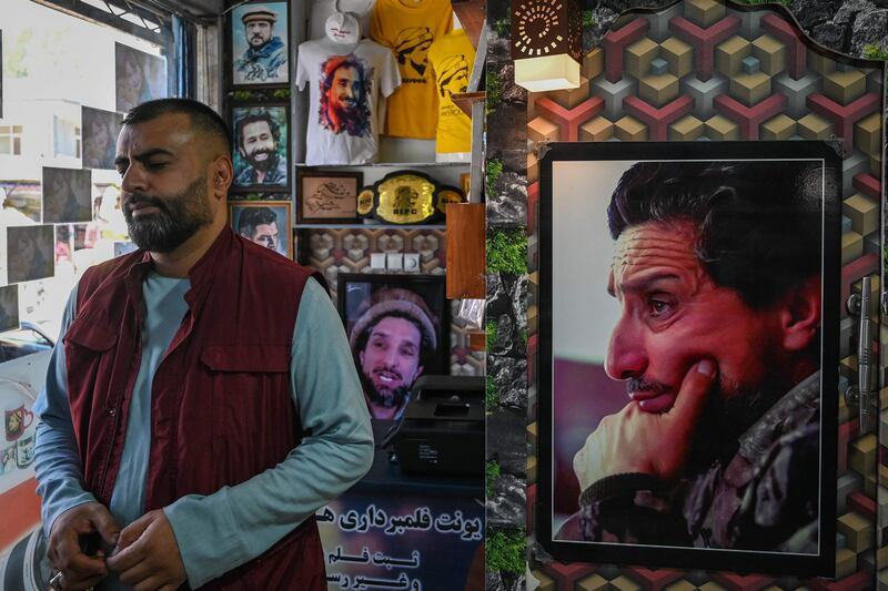 A shopkeeper in Kabul stands next to t-shirts and photo frames with pictures of late Afghan commander Ahmad Shah Massoud. AFP