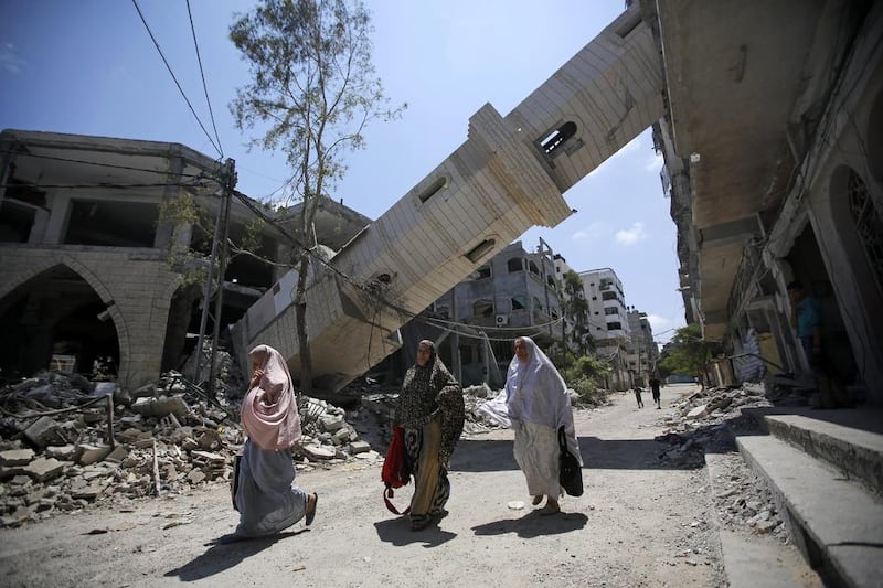 Palestinians walk under the minaret of a destroyed mosque in Gaza. Israel not only are profiting from the reconstruction but also turning the territory into a super-maximum prison. Photo: Mohammed Saber / EPA