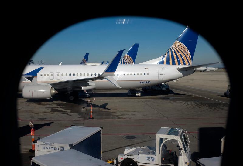 In this Nov. 22, 2017, photo taken through an aircraft passenger window, United Airlines planes are parked at a terminal at O'Hare International Airport in Chicago. United Continental Holdings, Inc. reports earnings, Tuesday, Jan. 23, 2018. (AP Photo/Kiichiro Sato)