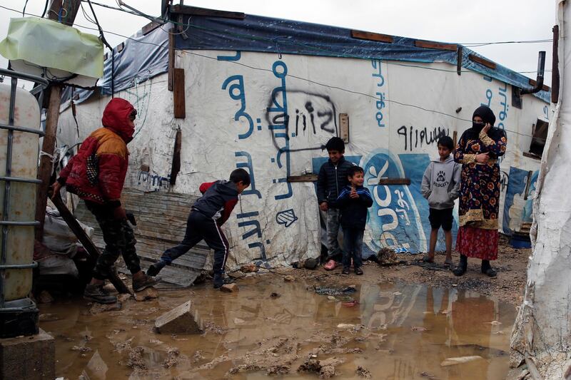 Syrian refugee children walk between tents in mud from a heavy rain at a refugee camp in the town of Bar Elias, in Lebanon's Bekaa Valley, Thursday, Jan. 3, 2019. Lebanon has seen unusually heavy rainfall this year, leaving tens of thousands of refugees in informal tented settlements struggling to deal with water and mud seeping into their tents. (AP Photo/Bilal Hussein)