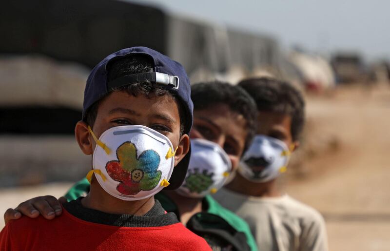 Displaced Syrian boys pose while wearing face masks decorated by artists during a Covid-19 awareness campaign at the Bardaqli camp in the town of Dana in Syria's north-west Idlib province. AFP