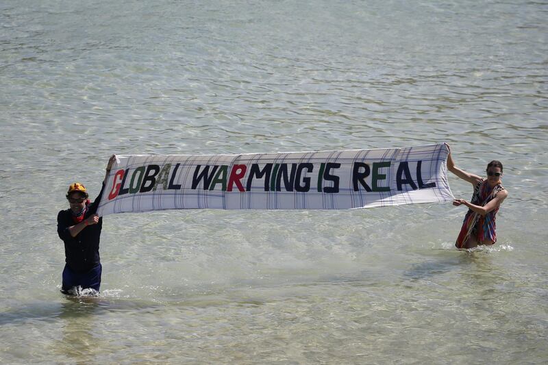 Extinction Rebellion protesters hold a sign that says "Global Warming is Real" in the sea on the sidelines of the final day of the Group of Seven leaders summit, in St. Ives, U.K., on Sunday, June 13, 2021. The worlds richest governments are under mounting pressure to help poor countries fight climate change. Photographer: Hollie Adams/Bloomberg