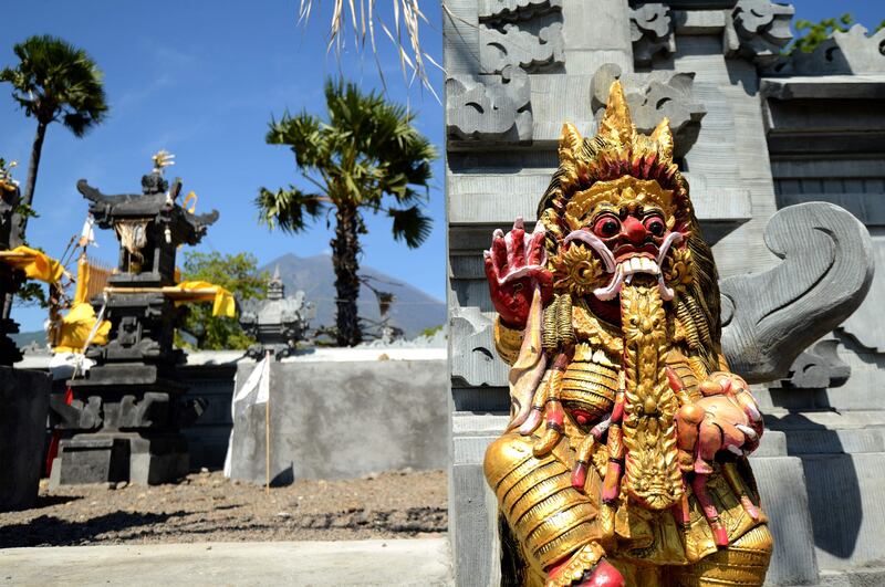 Statues at a Balinese temple are pictured as Mount Agung volcano looms in the background. Sonny Tumbelaka / AFP Photo