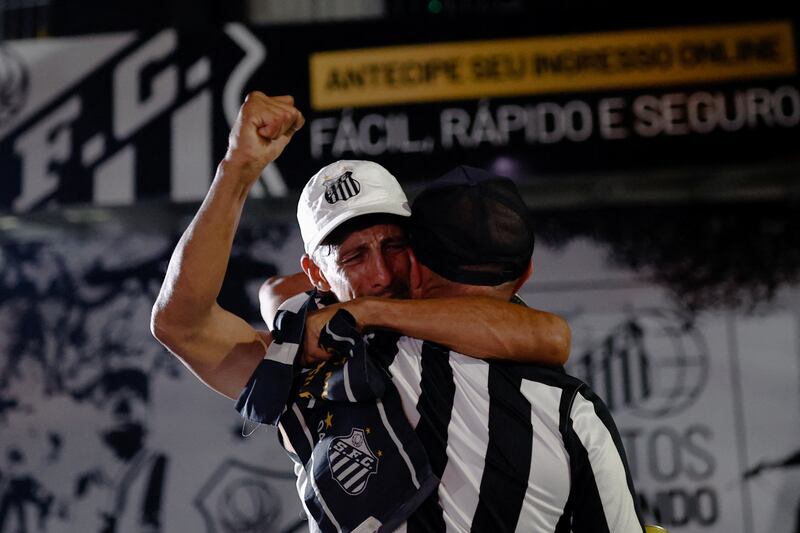 Fans of Brazilian soccer legend Pele embrace as they mourn his death, in Santos, Brazil, December 30, 2022.  REUTERS / Amanda Perobelli