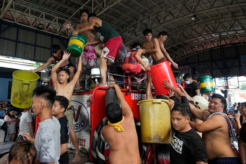 Residents fill plastic containers from a fire engine to fight a fire in Manila, Philippines. Authorities are still trying to investigate the cause of fire. No one was reported hurt in the incident. AP